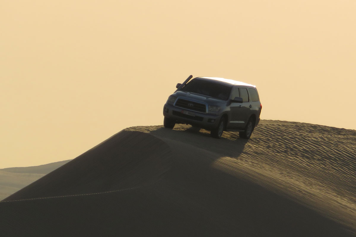 A jeep on a sand dune before sunset